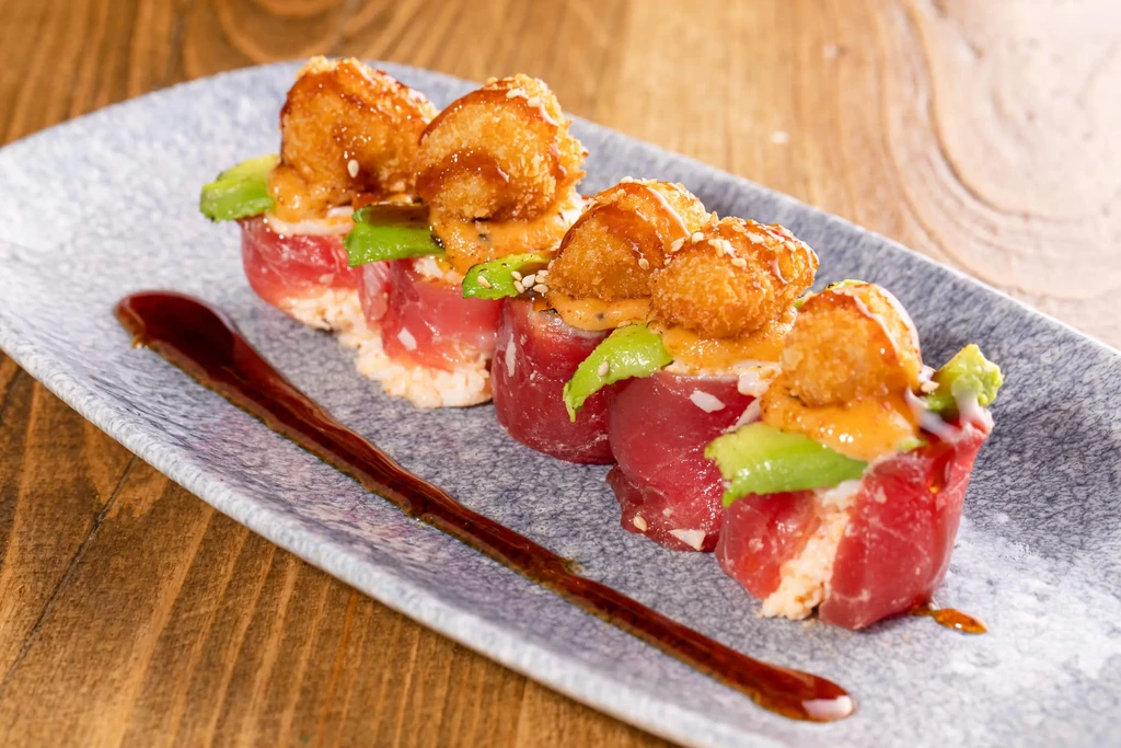 Four plated tuna and avocado sushi appetizers with crispy rice.
