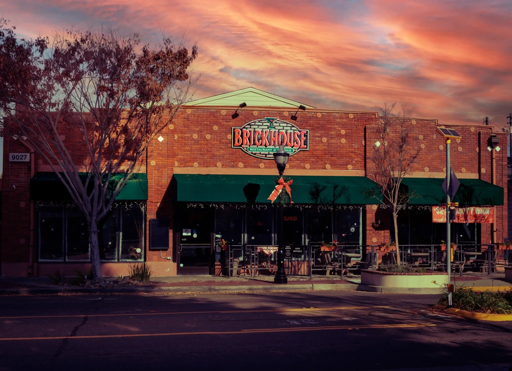 Brickhouse restaurant exterior with brick facade, awnings, outdoor seating at sunset.