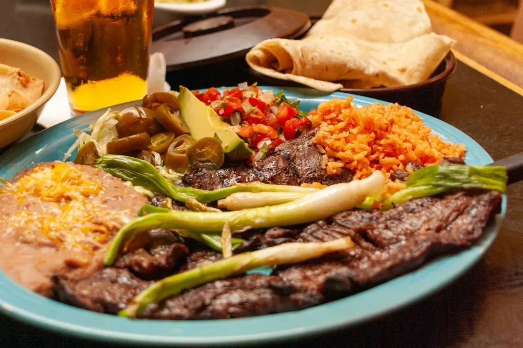 Vibrant Mexican grilled steak, rice, beans, avocado, and tortillas.