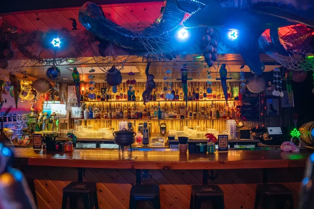 Vibrant, colorful tiki bar interior with illuminated bottles and decor.