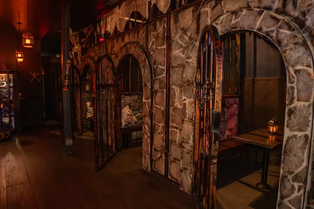 Pirate-themed restaurant interior with arched stone booths and lanterns.