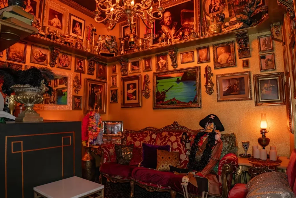 Dimly lit, ornate room features a skeleton pirate on a red velvet sofa.