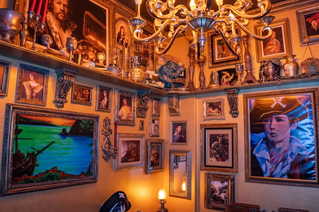 Eclectic room with ornate framed art, curios, and a pirate hat.