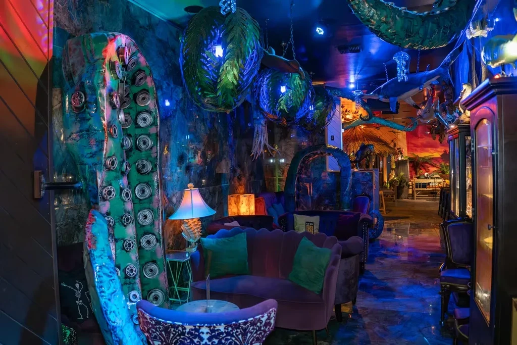 Dark, mystical restaurant with octopus tentacle, marine sculptures, blue lighting.