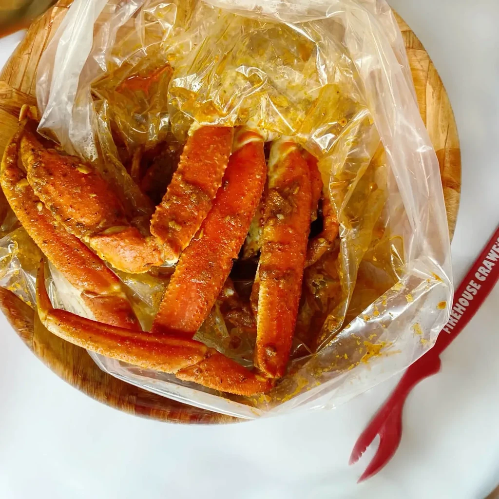 Overhead: Seasoned crab legs in bag, wooden bowl, red cracker.