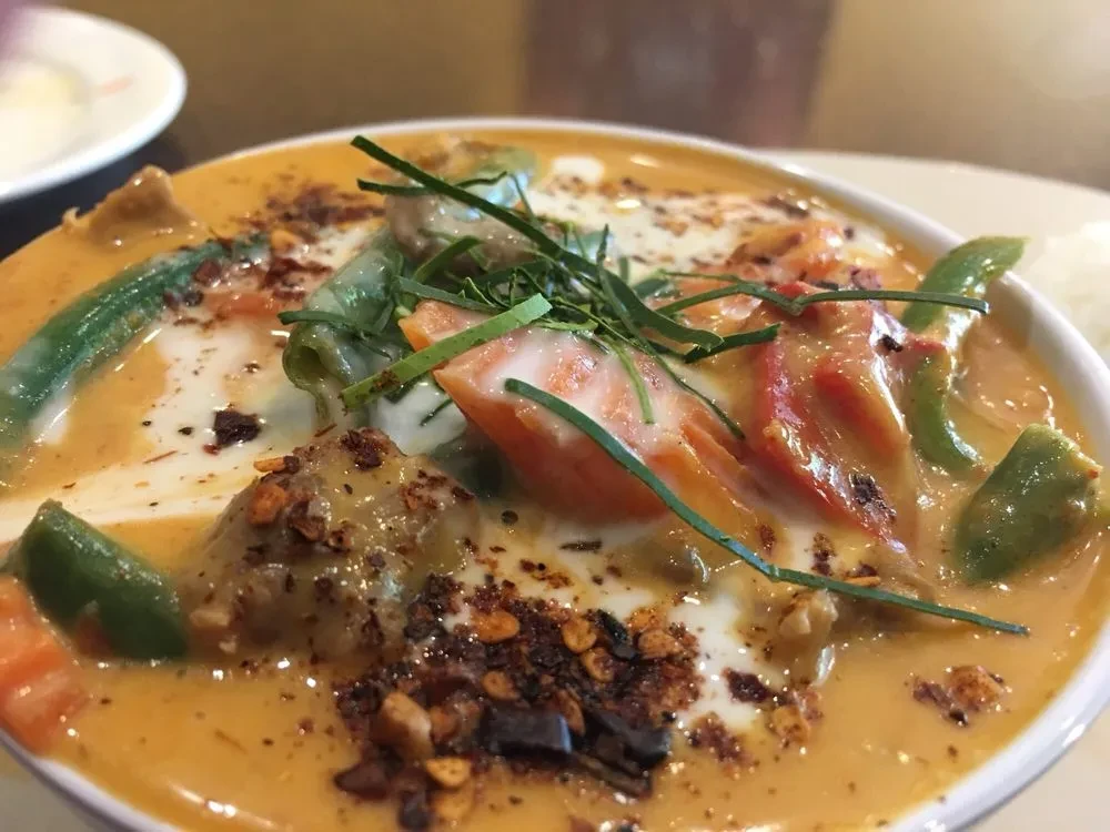 Vibrant Thai curry with coconut milk, vegetables, herbs, and chili flakes.