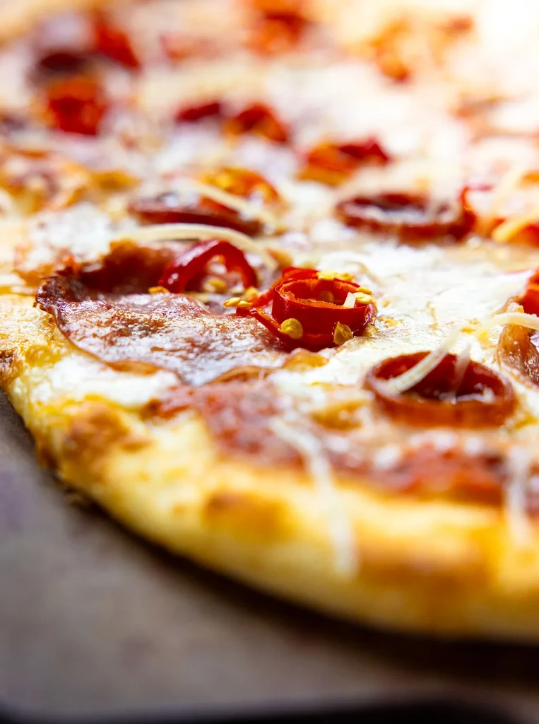 Freshly baked pepperoni pizza with melted cheese and red chili peppers.