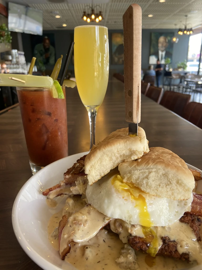 Close-up of chicken fried steak, egg, biscuit, Bloody Mary, and mimosa.