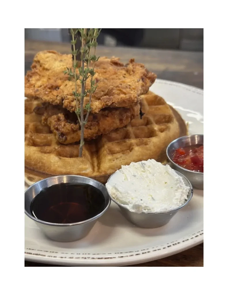 Crispy fried chicken and golden waffle with syrup, cream, and fruit compote.