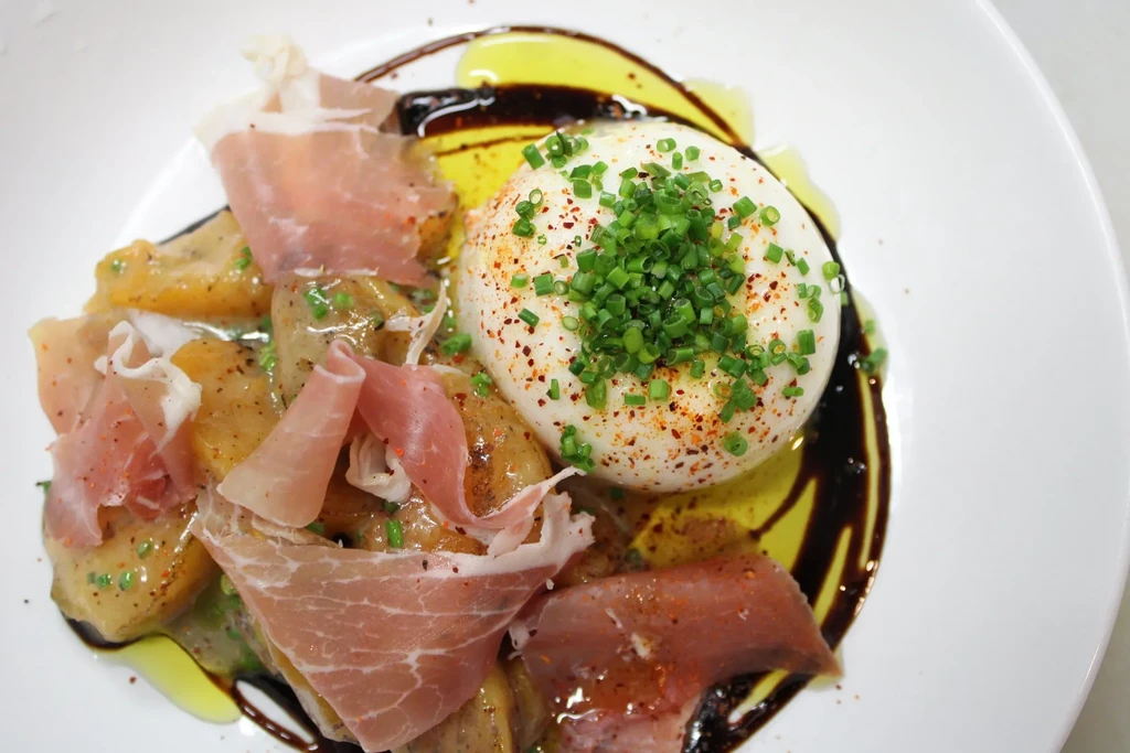 Overhead view: burrata with chives, prosciutto, gnocchi, oil, and balsamic.