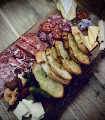 Charcuterie board with cured meats, assorted cheeses, bread, and accompaniments.