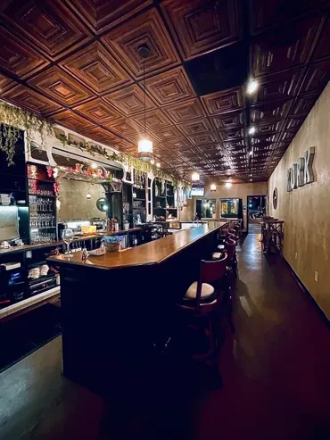 Dark wood restaurant bar interior with ornate ceiling and KORK sign.