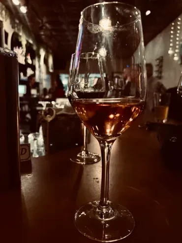 Wine glass with rosé liquid and crusted rim in a dim bar.