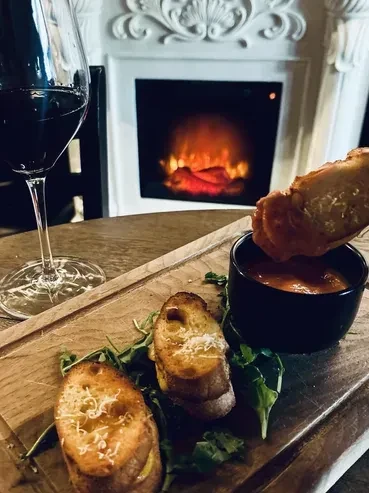 Crostini with cheese, a dip, red wine, and a warm fireplace.