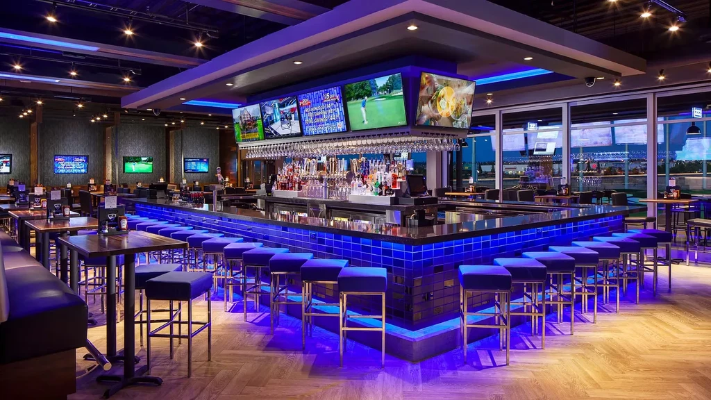 Vibrant bar and dining area with blue lighting and multiple TVs.