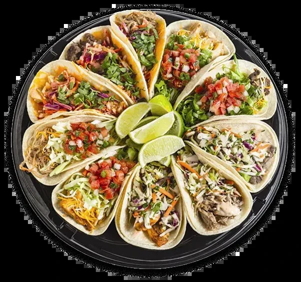 Circular platter filled with a dozen diverse tacos and lime wedges.