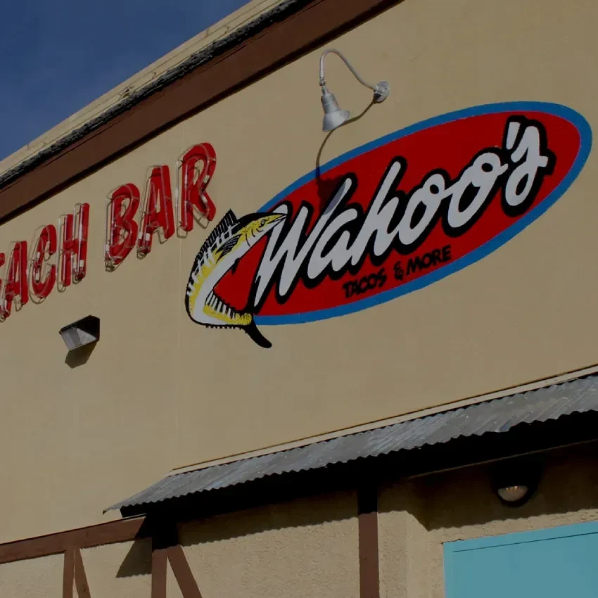 Wahoo's TACOS & MORE oval sign with fish logo on restaurant exterior.