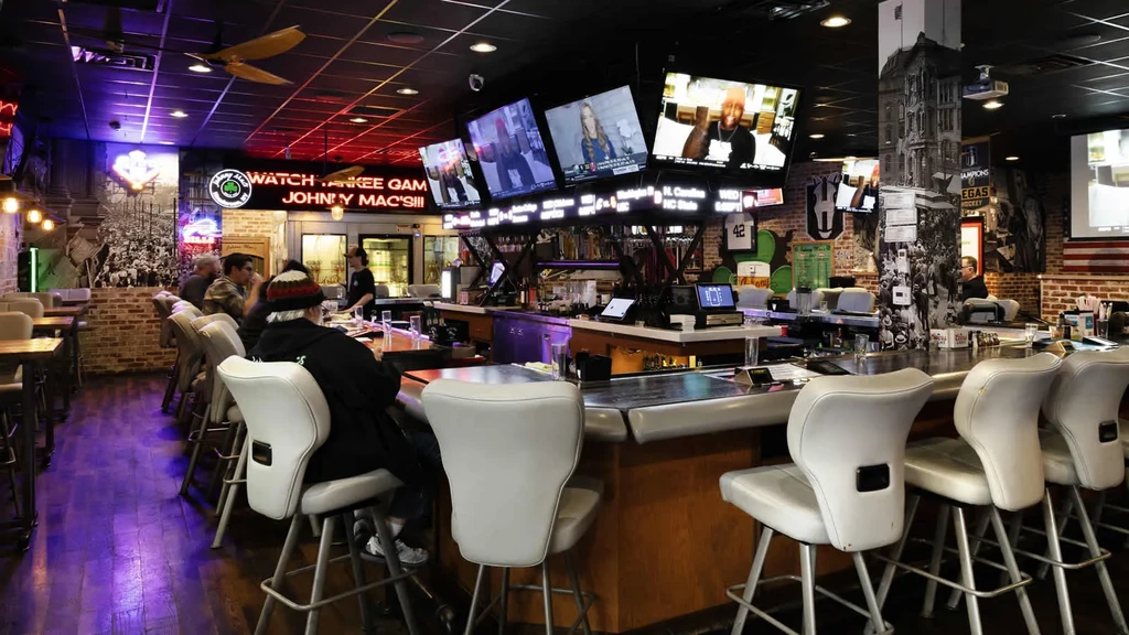 A lively, dimly lit sports bar with TVs and neon signs.