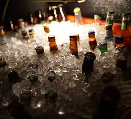 Assorted bottled beers and sodas submerged in crushed ice.