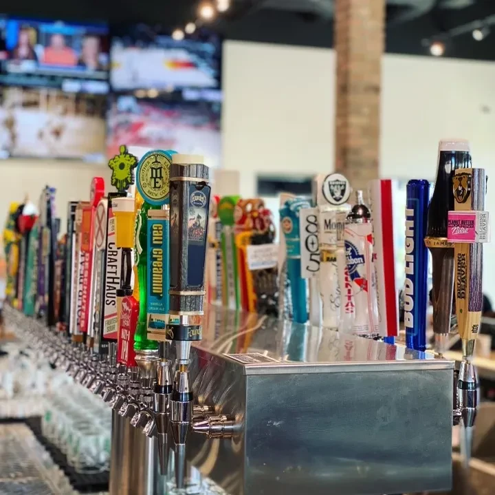 A long row of colorful beer taps at a modern sports bar.