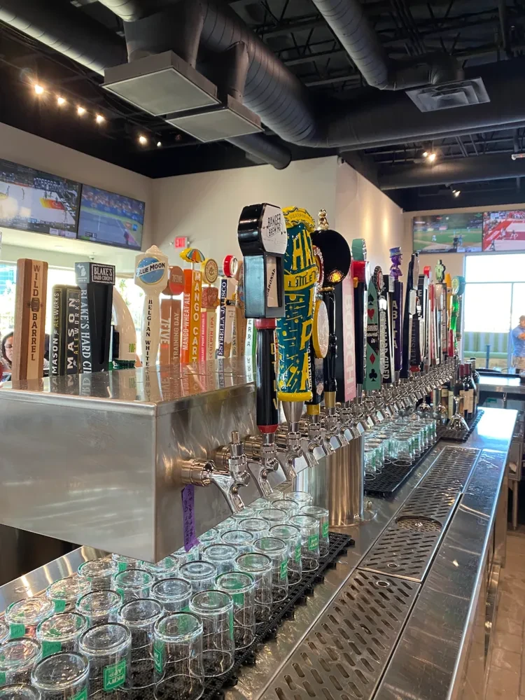 Brewpub bar with numerous beer taps, empty glasses, and TVs.