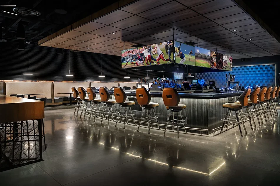 Empty modern sports bar with dark bar, leather stools, sports screens.