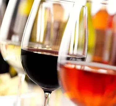 Wine glasses with rosé, red, and white wines in a row.