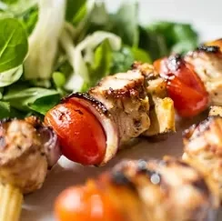 Charred chicken and tomato skewer served with green salad.