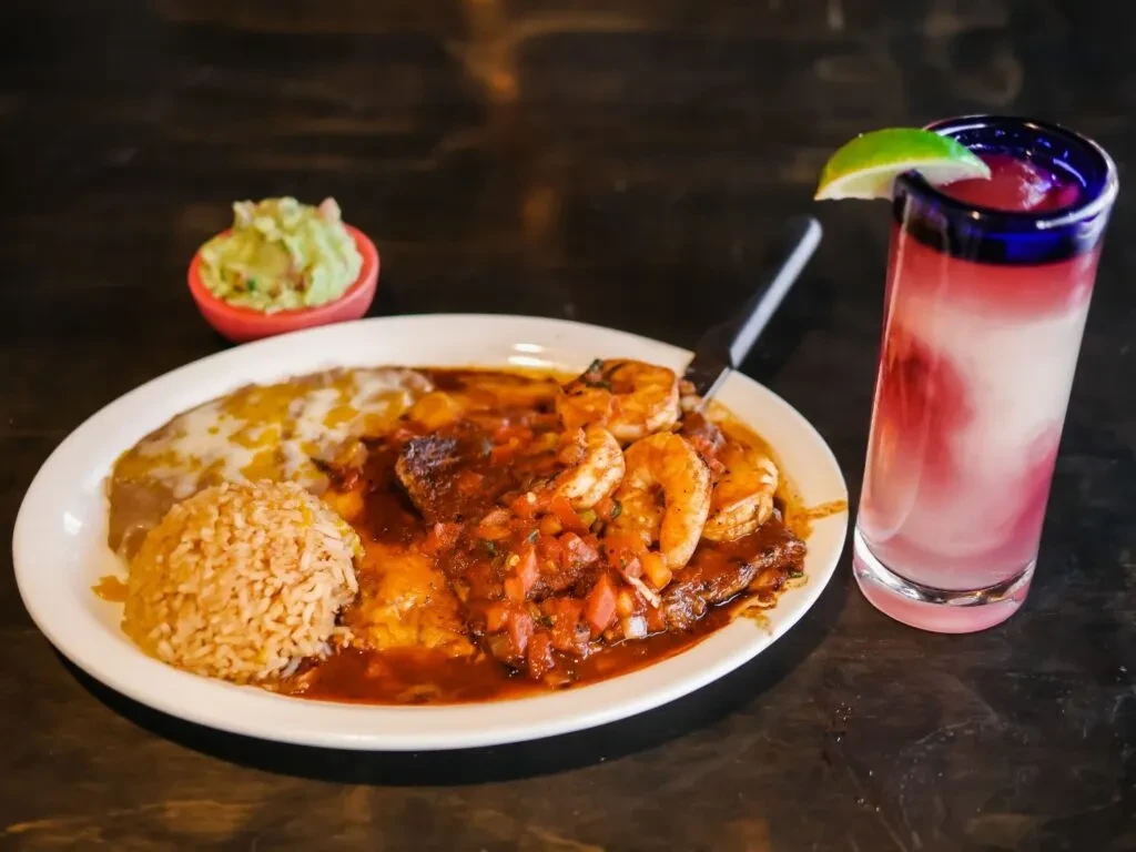 Mexican food: shrimp, rice, beans, and a pink layered drink.