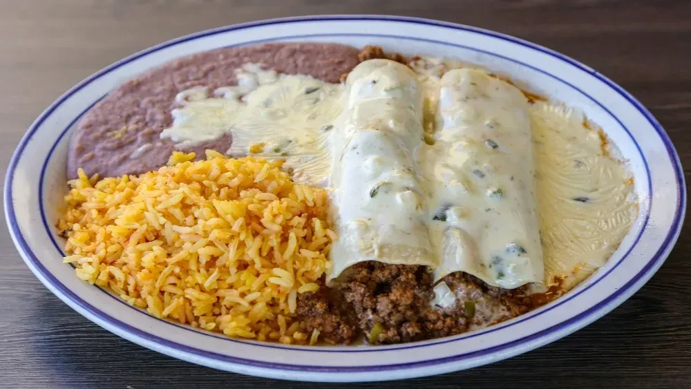 Plate of green enchiladas, Mexican rice, and cheesy refried beans.
