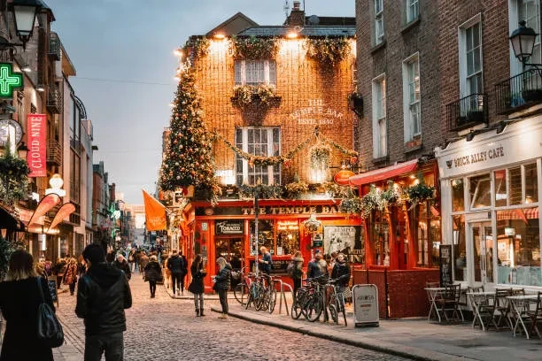 Festively decorated Temple Bar pub on a bustling cobblestone street.
