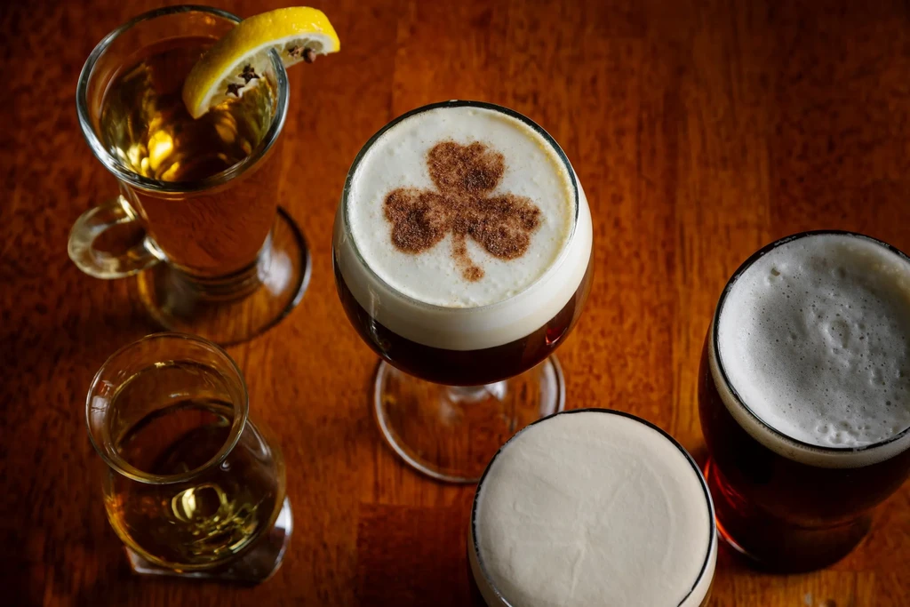 Overhead view of five distinct alcoholic drinks on a wooden surface.