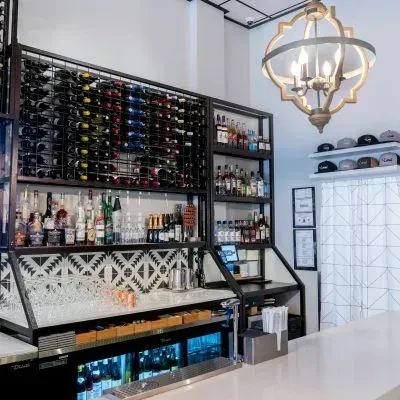 Well-stocked modern bar interior with geometric tiled wall.