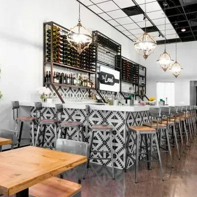 Modern bar interior with geometric counter, wine shelves, and 'The Local' logo.