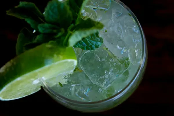 Close-up, top-down mojito with crushed ice, fresh mint, and lime.