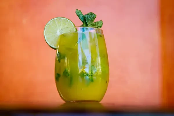Light green cocktail in stemless glass with lime and mint.