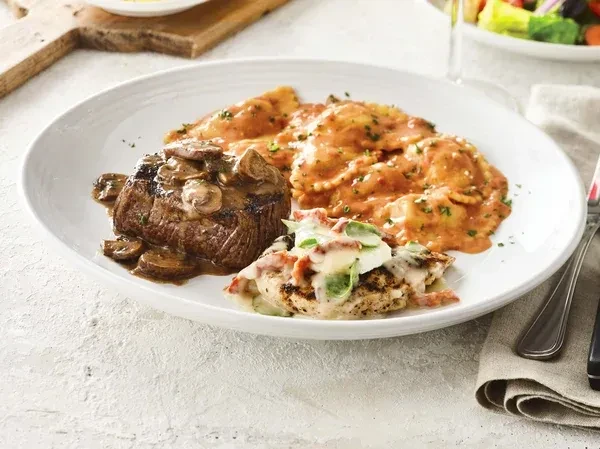 Beautifully plated meal with steak, ravioli, and grilled chicken.