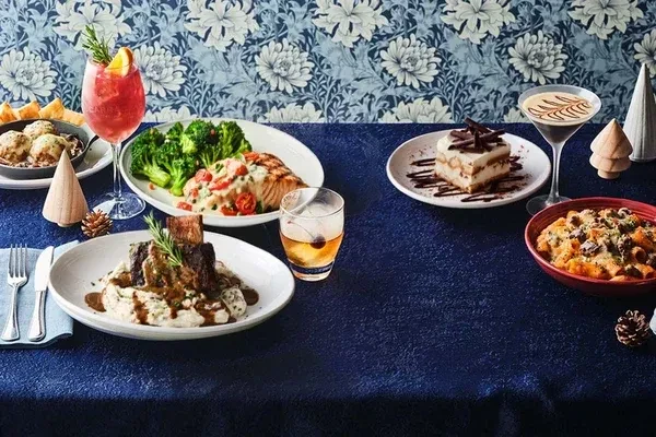 Festive dining table displays various elegant dishes, cocktails, and desserts.