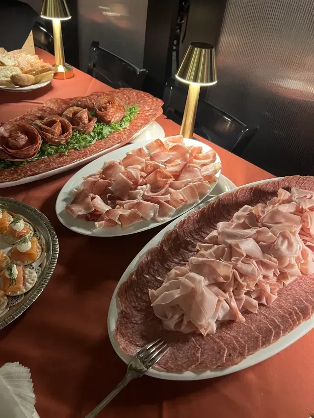 Buffet table with meticulously arranged cured meats, ham, and salmon crackers.