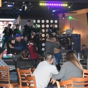 Lively indoor scene: band plays, couples dance, patrons sit.