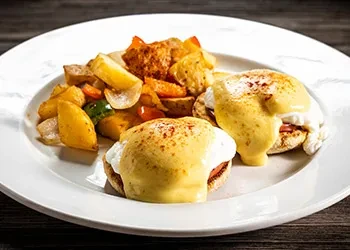 Two Eggs Benedict with hollandaise and home-fry potatoes.