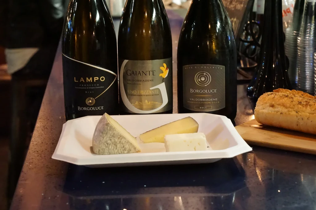 Sparkling wine bottles, cheese, and bread on a counter.