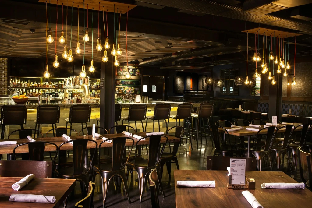 Empty industrial-chic restaurant and bar with colorful Edison bulbs.