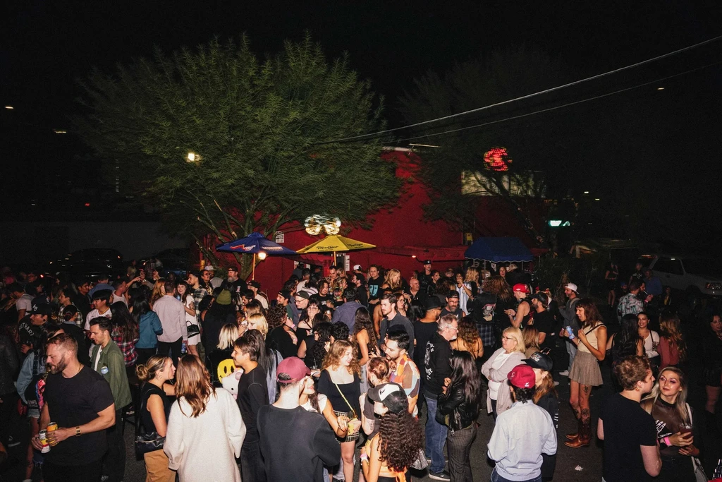 Dense crowd of young adults socializing at an outdoor night bar.