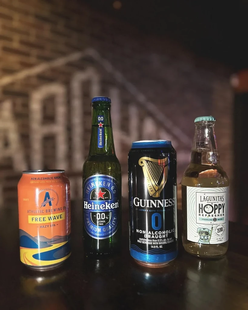 Non-alcoholic IPA, lager, stout, and sparkling water on a dark surface.