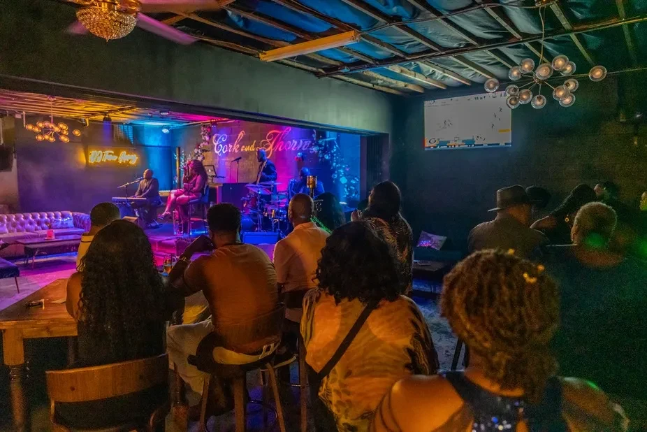 Lively bar interior with patrons watching a brightly lit live band.