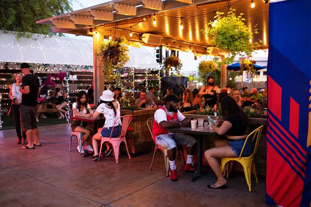 Lively outdoor patio at dusk with patrons under string lights.
