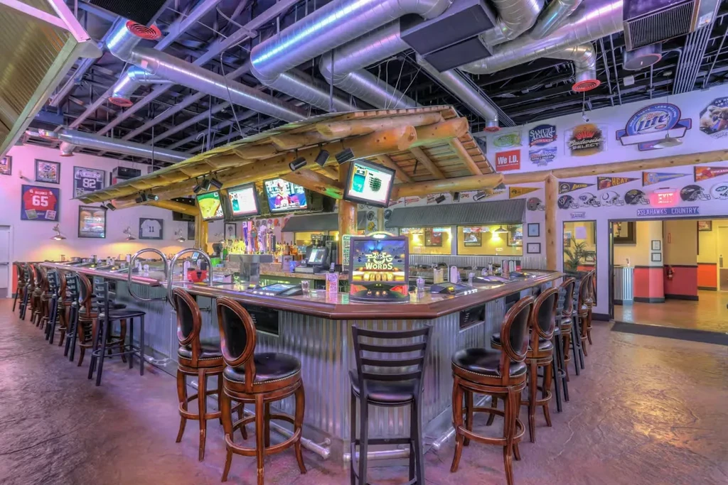 Empty sports bar with a U-shaped bar, TVs, and sports memorabilia.