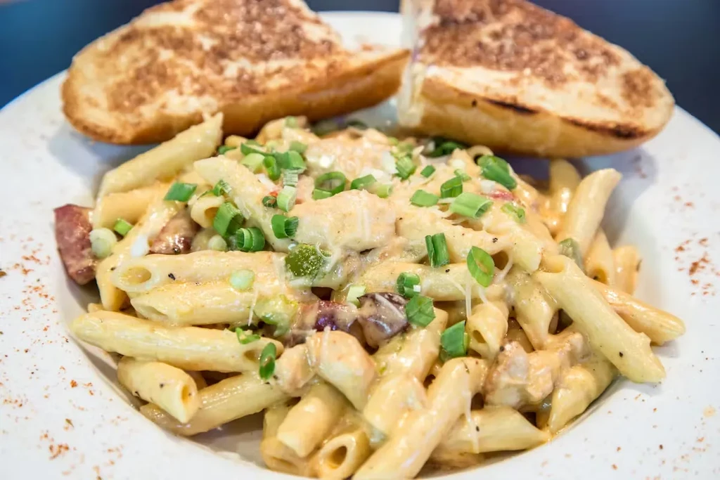 Creamy penne pasta with chicken, green onions, and garlic bread.
