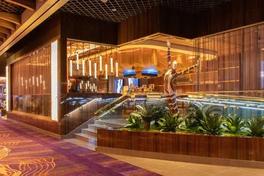 Luxury bar interior with grand staircase, tropical plants, and modern sculpture.